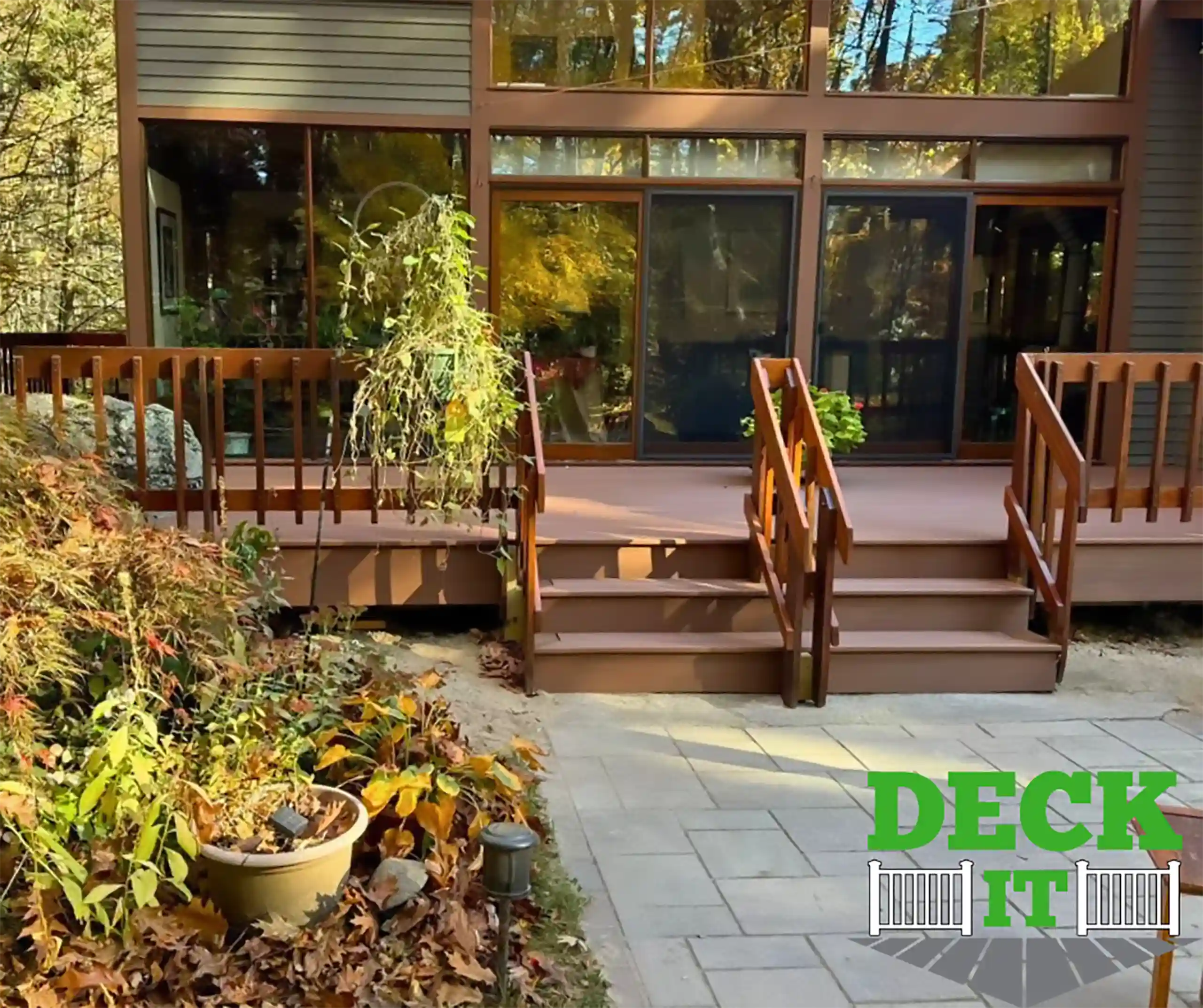 Custom Trex deck with Foggy Wharf boards and white composite railings, leading to a patio area with surrounding greenery.